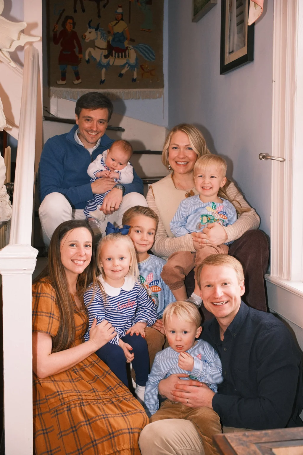Family with young children seated together on the stairs at home